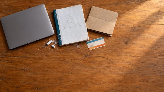 Lifelong learning news roundup: classroom desk with laptop, maths workbook and protest placard